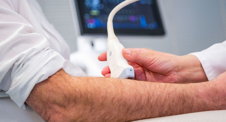 Gefäßchirurgie Ärztin untersucht Arm eines Patienten mit Ultraschall